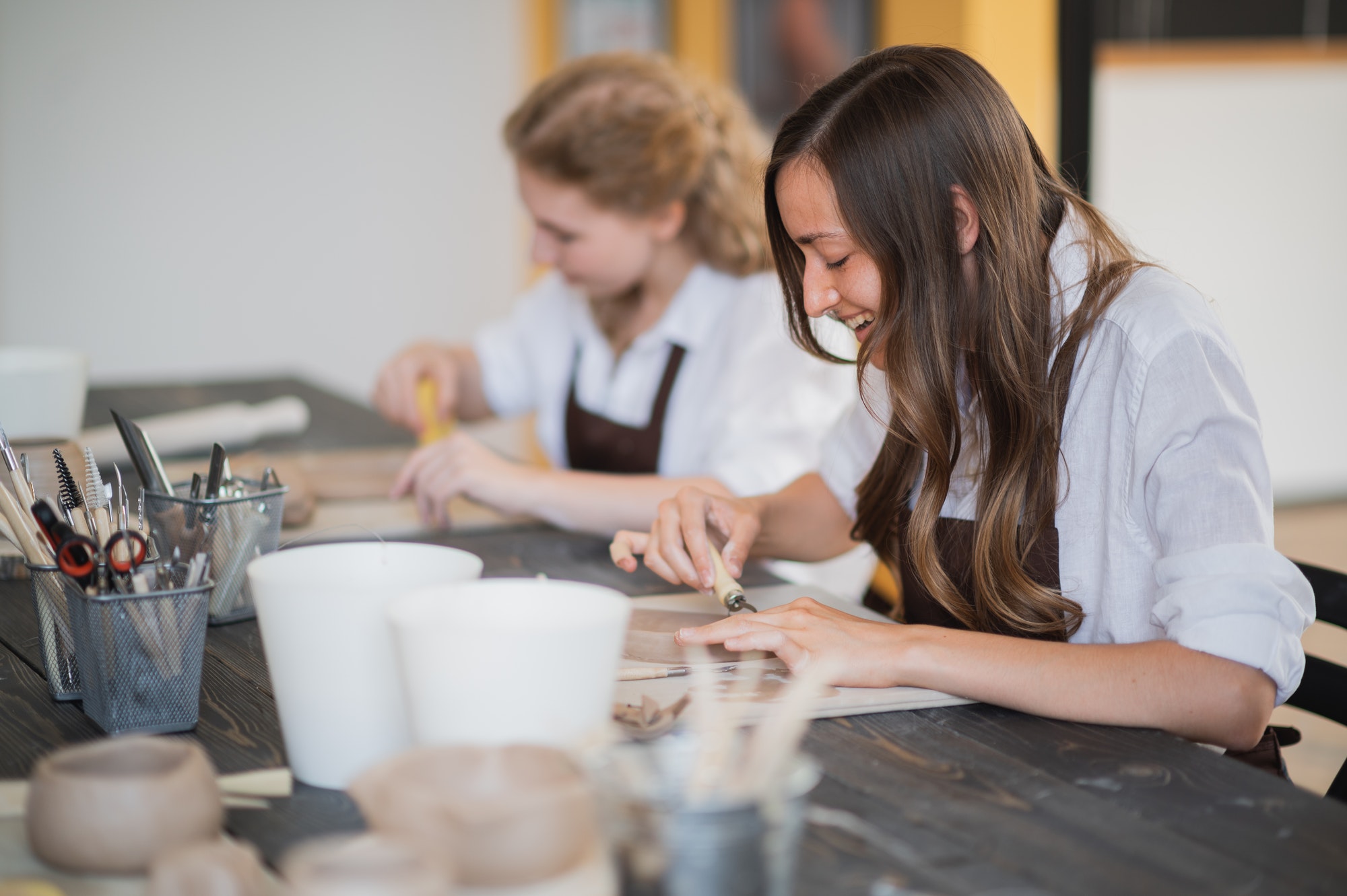 Beautiful young female artist girls creating handmade pottery in modern art studio. Education kids